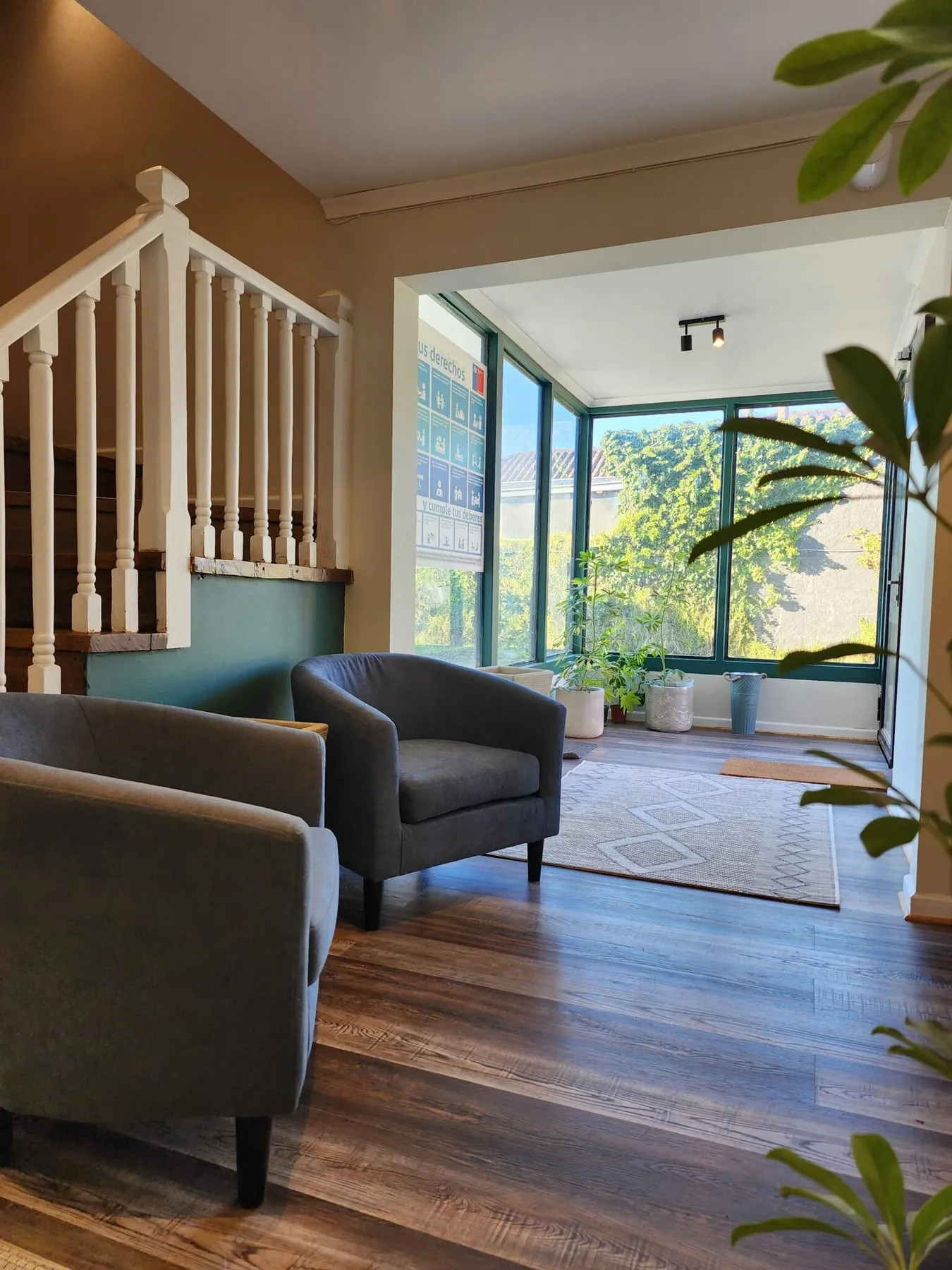 Sala de espera con sillones junto a ventanales hacia el jardín